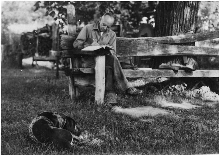 Aldo Leopold writing at his shack near Baraboo, Wisconsin with dog Flick, 1930-1939. Aldo Leopold Foundation and UW-Madison Archives.