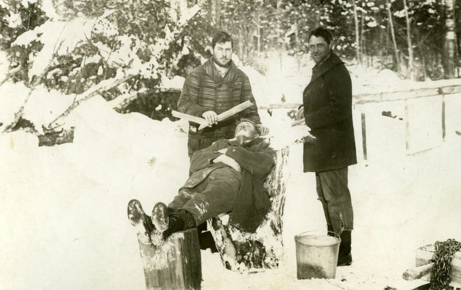 Loggers clown for the photographer as one shaves another. Langlade County Historical Society.
