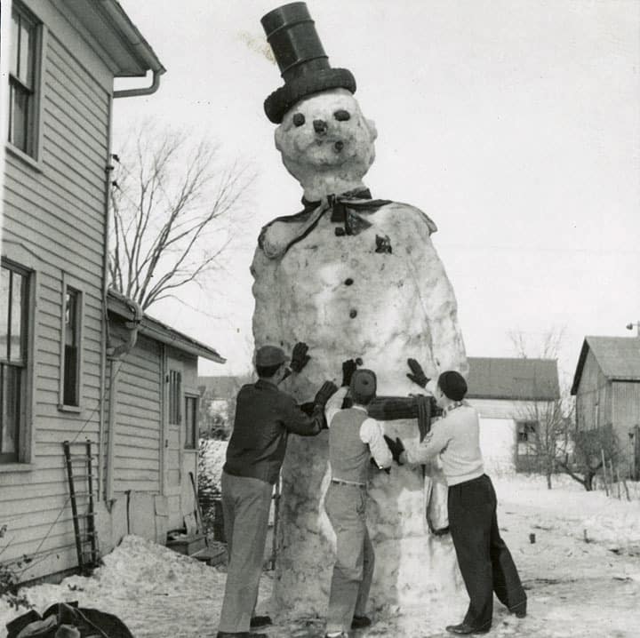 Three young men put the finishing touches on a huge snowman, Kiel, Manitowoc County. Big Streets in a Little City: Kiel, Wisconsin, 1860-1980, Heritage Collection, Kiel Public Library by way of University of Wisconsin Digital Collections