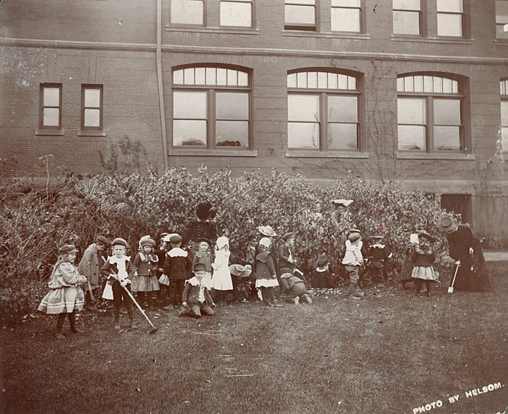 A kindergarten class and three teachers tend a garden outside Bowman Hall on the Stout campus, ca. 1900. University of Wisconsin-Stout.