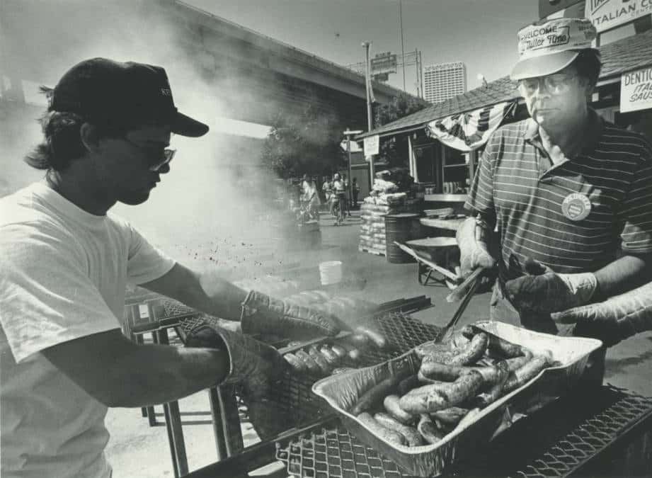 Two men cooking Italian sausages at Milwaukee's Festa Italiana, 1984. Photo by Michael Sears. Milwaukee Public Library.
