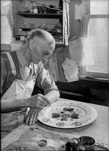 Per Lysne rosemaling a smorgasbord platter, Stoughton, ca. 1941. Photo by Arthur M. Vinje. Wisconsin Historical Society image ID 38105.