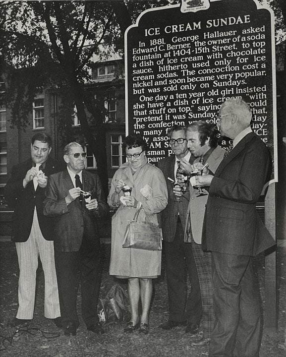 Joseph Schmitt, Seymour Althen, Henry Willert, Howard Messerman and Hilary Rath eating ice cream in front of Ice Cream Sundae historical marker, Two Rivers. Photo by Hubert R. Wentorf. Lester Public Library.