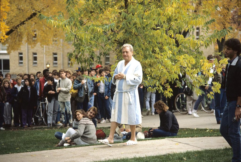 Students watch as Rodney Dangerfield strolls Bascom Hill in bathrobe and slippers between takes for Back to School. UW-Madison Archives via University of Wisconsin Digital Collections.