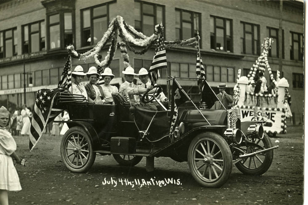 Street scene of Antigo. July 4th parade showing a decorated automobile. 1911-07-04. Antigo, Wisconsin. 
Langlade County Historical Society.
