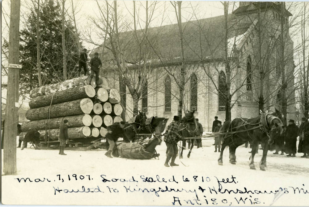 Logging. Horses hauling logs to Kingsbury and Henshaw mill in Antigo. St. John's Catholic Church is clearly in view in the background. 1907-03-07. Antigo, Wisconsin. 
Langlade County Historical Society. 