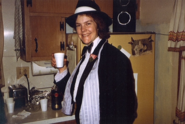 Lois Blank in a tux and matching hat, holding a cup, at the 1983 Tux Party.