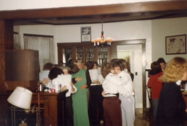 Tux Party from 1980. It pictures multiple lesbian couples dancing in embraces in a member's living room. They are either wearing tuxes or other fancy outfits.
