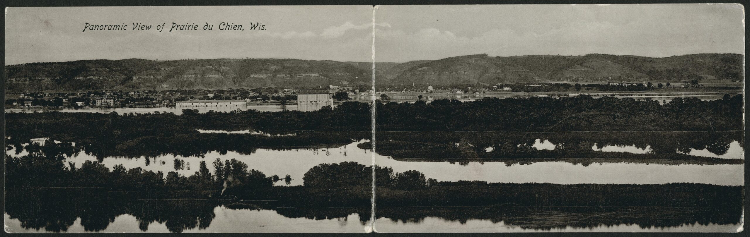 A postcard of a panoramic view of the town of Prairie du Chien with the Mississippi River in the foreground and bluffs in the background in November, 1911.