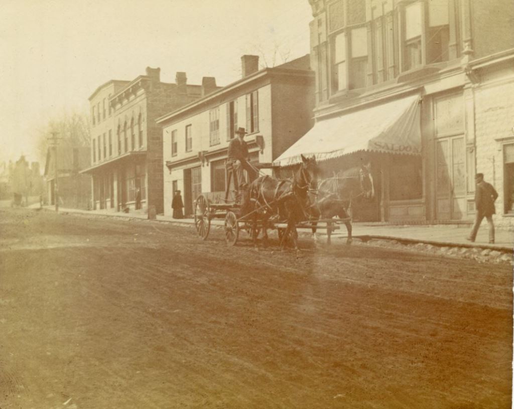 Bob James drives his horse drawn wagon down High Street in Mineral Point; note on back of photograph: Bob James, West end of High Street north side. Undated.