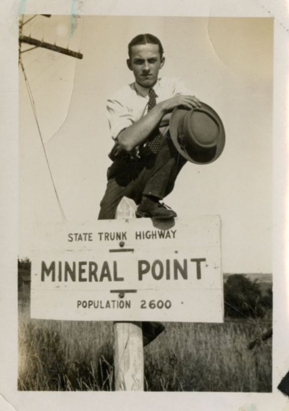 Man perched on Mineral Point highway sign