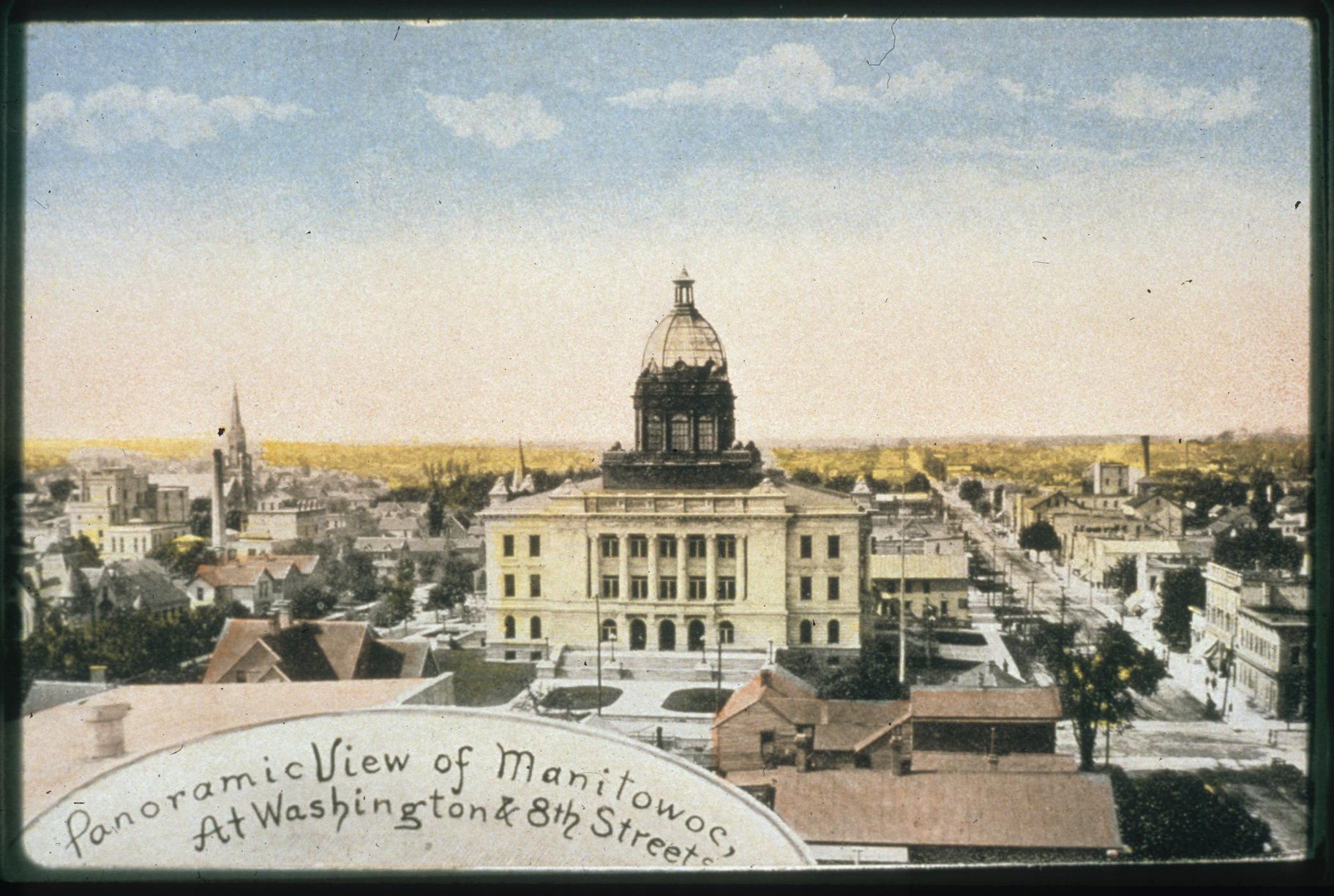 "Panoramic view of Manitowoc at Washington & Eighth St.": tinted postcard by Hermann Benke. The view looks west and must have been taken later than 1906 when the new courthouse was erected.