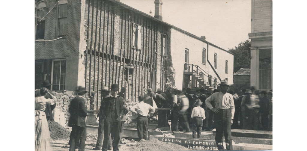 Cave-in at Cambria, Wis. postcard, 1909. People looking at collapse of building.