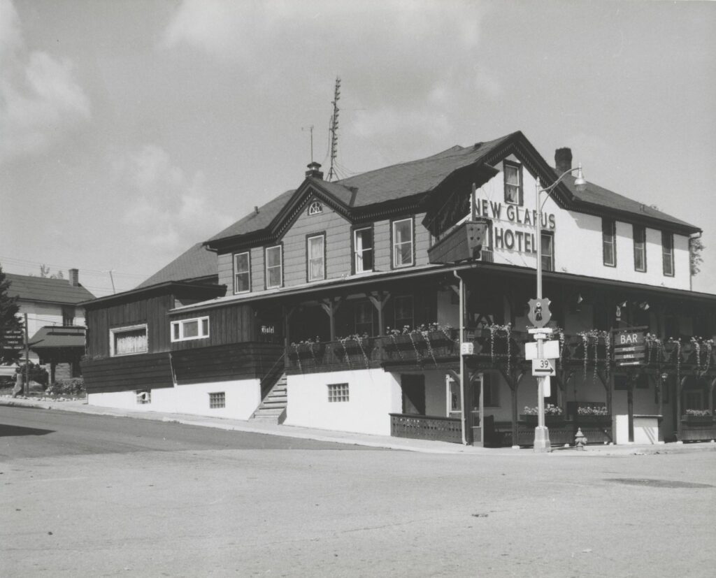 The New Glarus Hotel at the intersection of First Street and Fifth Avenue, as it appeared in the 1960s. Built in 1853 and originally called New Glarus Haus, it was the first hotel in New Glarus. The New Glarus Hotel no longer functions as a hotel but the restaurant is still in business.