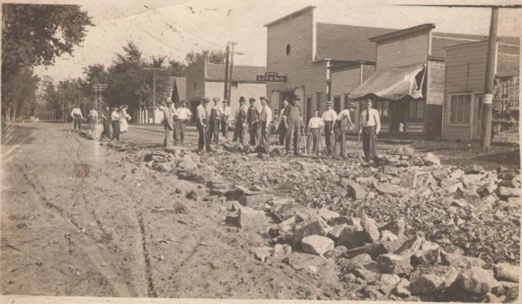 Postcard of a group of men making repairs to Main Street in 1914. The Crystal Theatre and Moore's Livery are pictured.