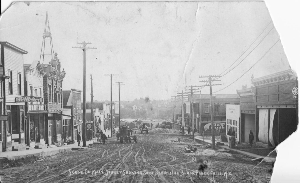 Postcard of the rebuilding of Main Street after a flood in 1911. Businesses pictured are Hotel Hamon Restaurant and Badger State Banner building. Postcard was sent to Richard Lang. Owned by Grace Nordahl.