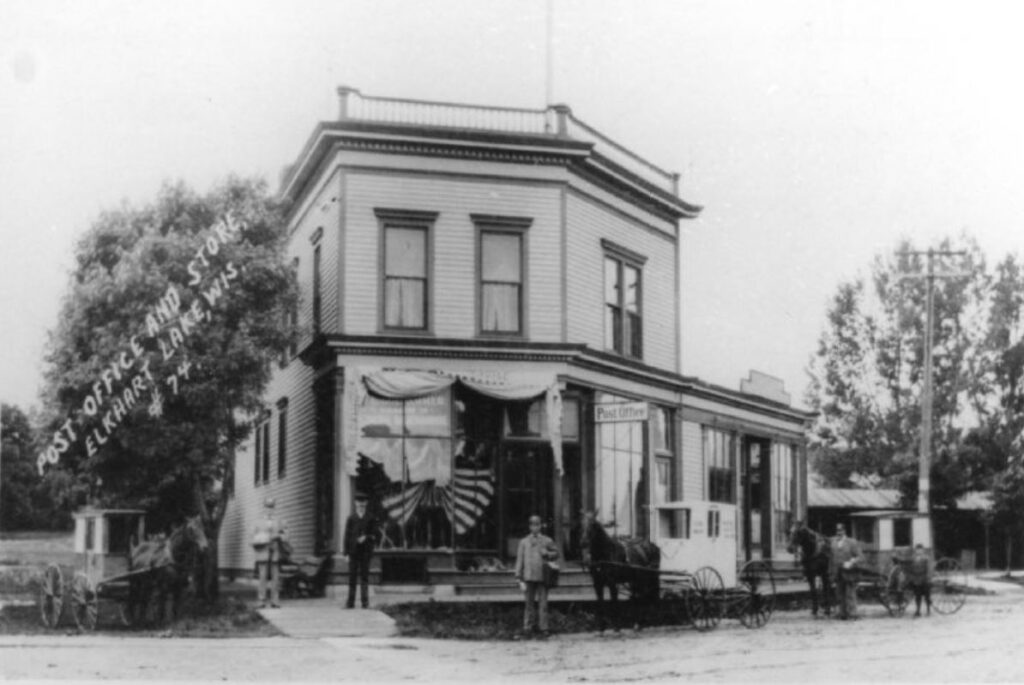 Men and horses and wagons in front the Post Office and store, Elkhart Lake, Wisconsin, 1873.