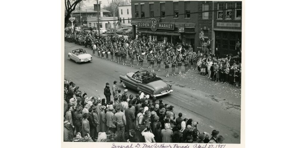 A Parade (April 27, 1951) honoring the homecoming of Milwaukee of General Douglas MacArthur, two weeks after he was relieved of his duties as Commander of UN Forces in the Korean War. MacArthur’s grandfather lived in Milwaukee and served as Wisconsin’s Lt. Governor and MacArthur considered Milwaukee to be his ancestral home. The South Milwaukee Fire Department, VFW Post, and A & P Super Market store are seen in the background. The original South Milwaukee Public Library building is seen in the upper left corner.
