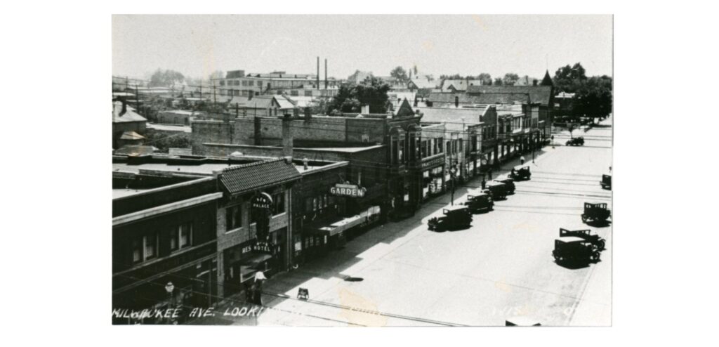 This postcard shows an elevated view west of the stores and buildings along the 1000 block of Milwaukee Avenue. Lichte’s Pharmacy, the New Palace Hotel, and the Garden Theater are among those seen.
