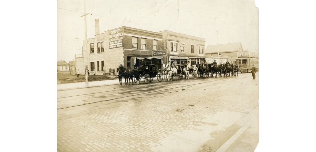 Street scene, Milwaukee Avenue, 1916. View looking northeast of the 900 block of Milwaukee Avenue. An identified horse and carriage team and the South Milwaukee streetcar are seen. Smoot’s Photography Studio, 914 Milwaukee Avenue, is seen in the background.